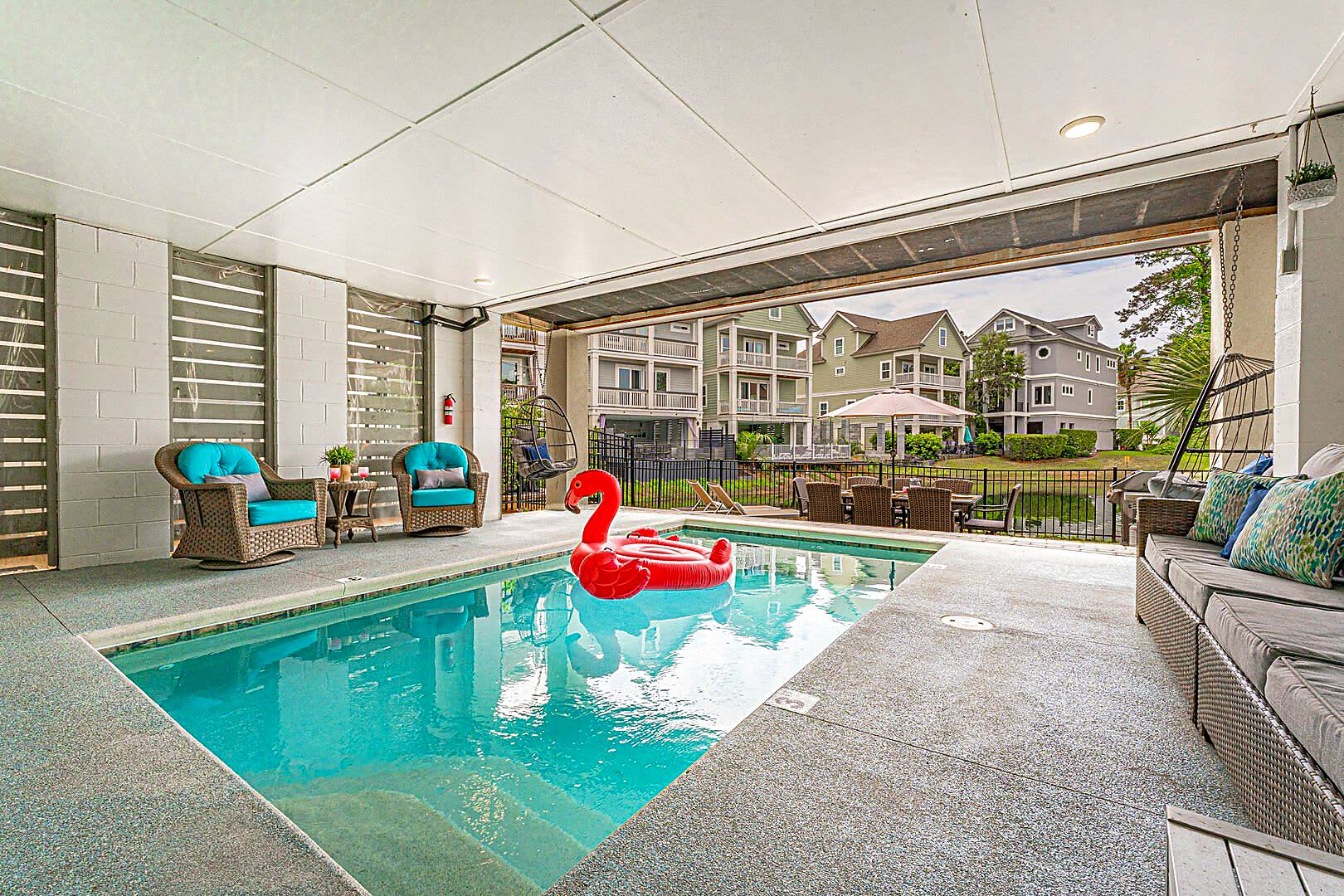 Heated private pool beneath 122 Sandcastle Court with the roll-up door open to the lagoon and neighbouring houses beyond