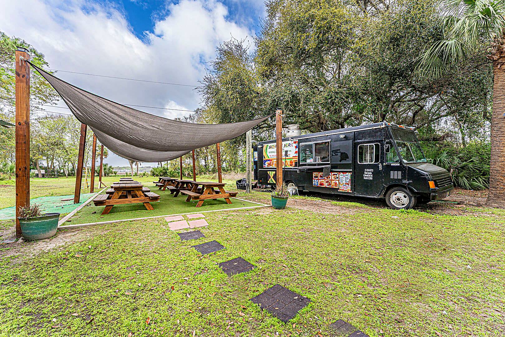 Food truck and picnic tables under a shade sail at Barnacle Bill's food truck park, Hilton Head Island